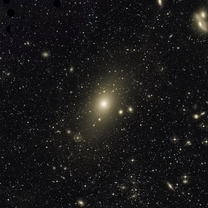 The huge halo around giant elliptical galaxy Messier 87 appears on this very deep image. An excess of light in the top-right part of this halo, and the motion of planetary nebulae in the galaxy, are the last remaining signs of a medium-sized galaxy that recently collided with Messier 87. The image also reveals many other galaxies forming the Virgo Cluster, of which Messier 87 is the largest member. In particular, the two galaxies at the top right of the frame are nicknamed 