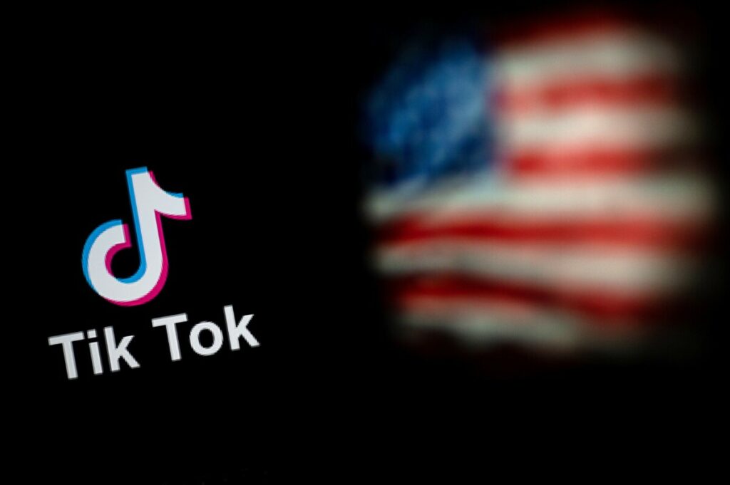 This photo illustration taken on September 14, 2020 shows the logo of the social network application TikTok (L) and a US flag (R) shown on the screens of two laptops in Beijing. - US tech giant Microsoft said on September 13 its offer to buy TikTok was rejected, leaving Oracle as the sole remaining bidder ahead of the imminent deadline for the Chinese-owned video app to sell or shut down its US operations. (Photo by NICOLAS ASFOURI / AFP)